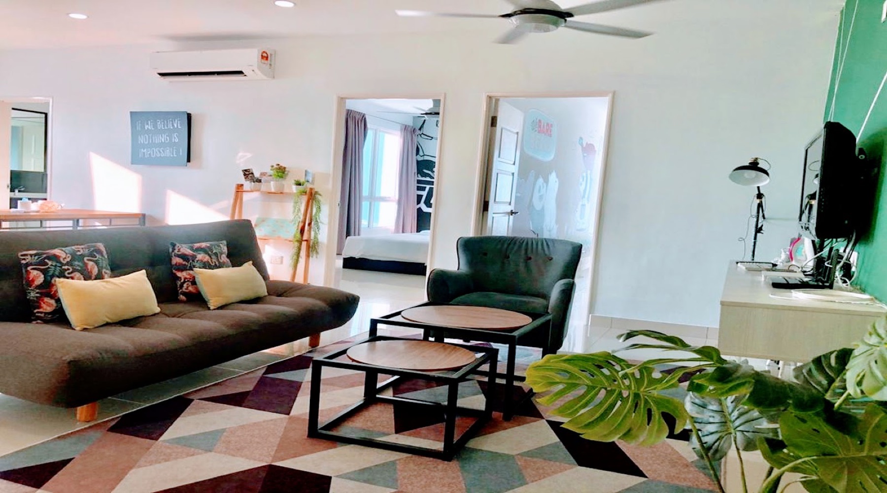 Two-bedroom suite living room with a sofa, dining nook and two bedroom doorways at Merlene Suites